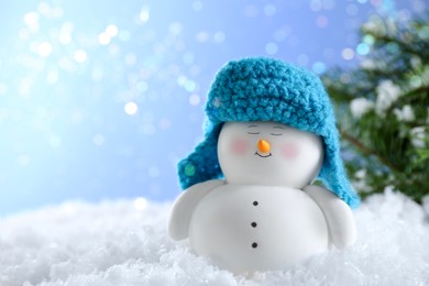 Photo of Cute decorative snowman on artificial snow against blurred lights, closeup. Space for text