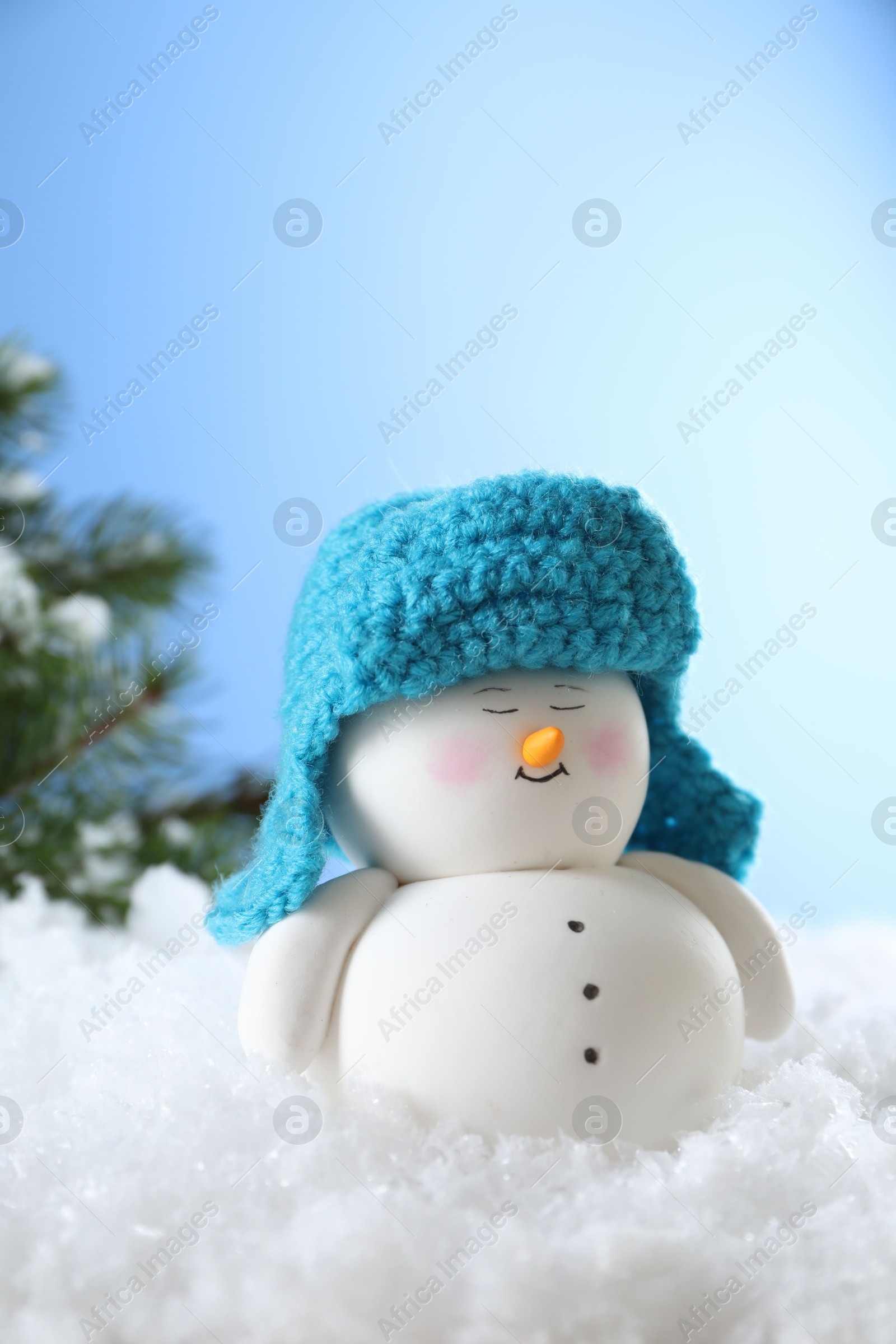 Photo of Cute decorative snowman on artificial snow against light blue background