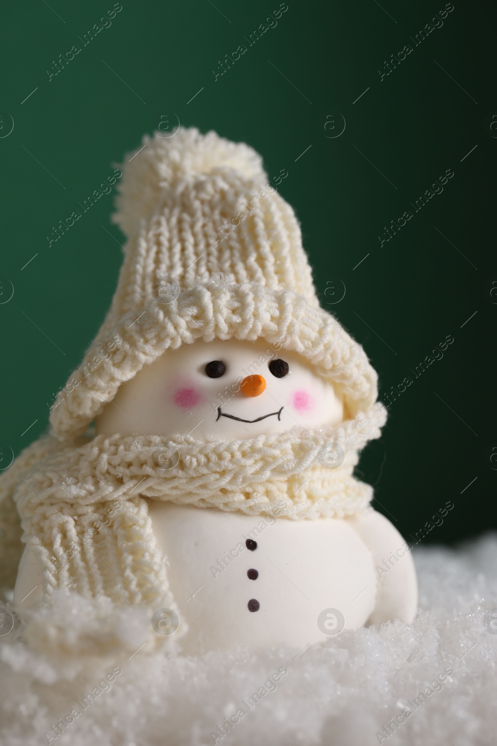 Photo of Cute decorative snowman on artificial snow against green background