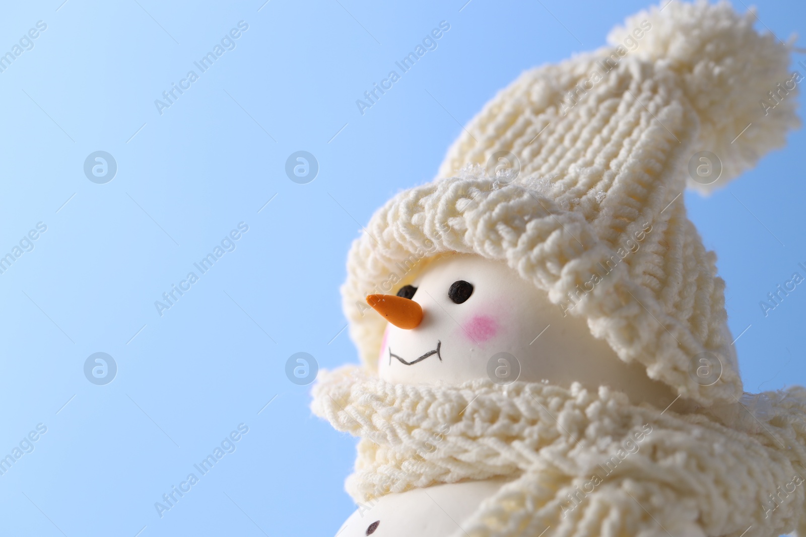 Photo of Cute decorative snowman against light blue background, closeup. Space for text