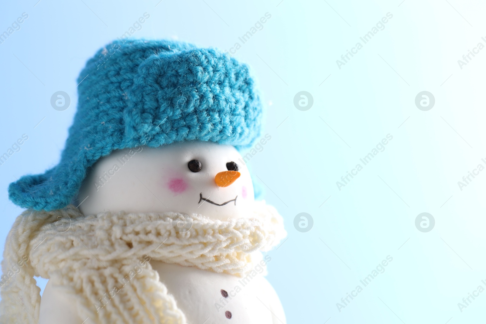 Photo of Cute decorative snowman against light blue background, closeup. Space for text