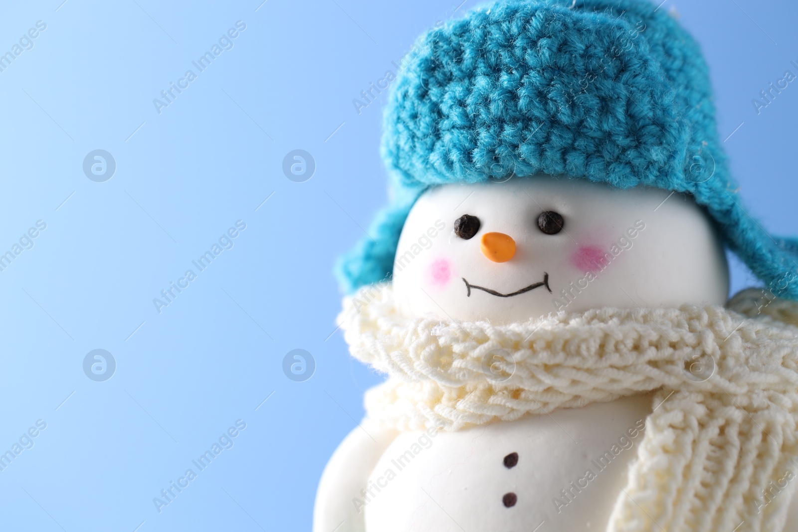 Photo of Cute decorative snowman against light blue background, closeup. Space for text