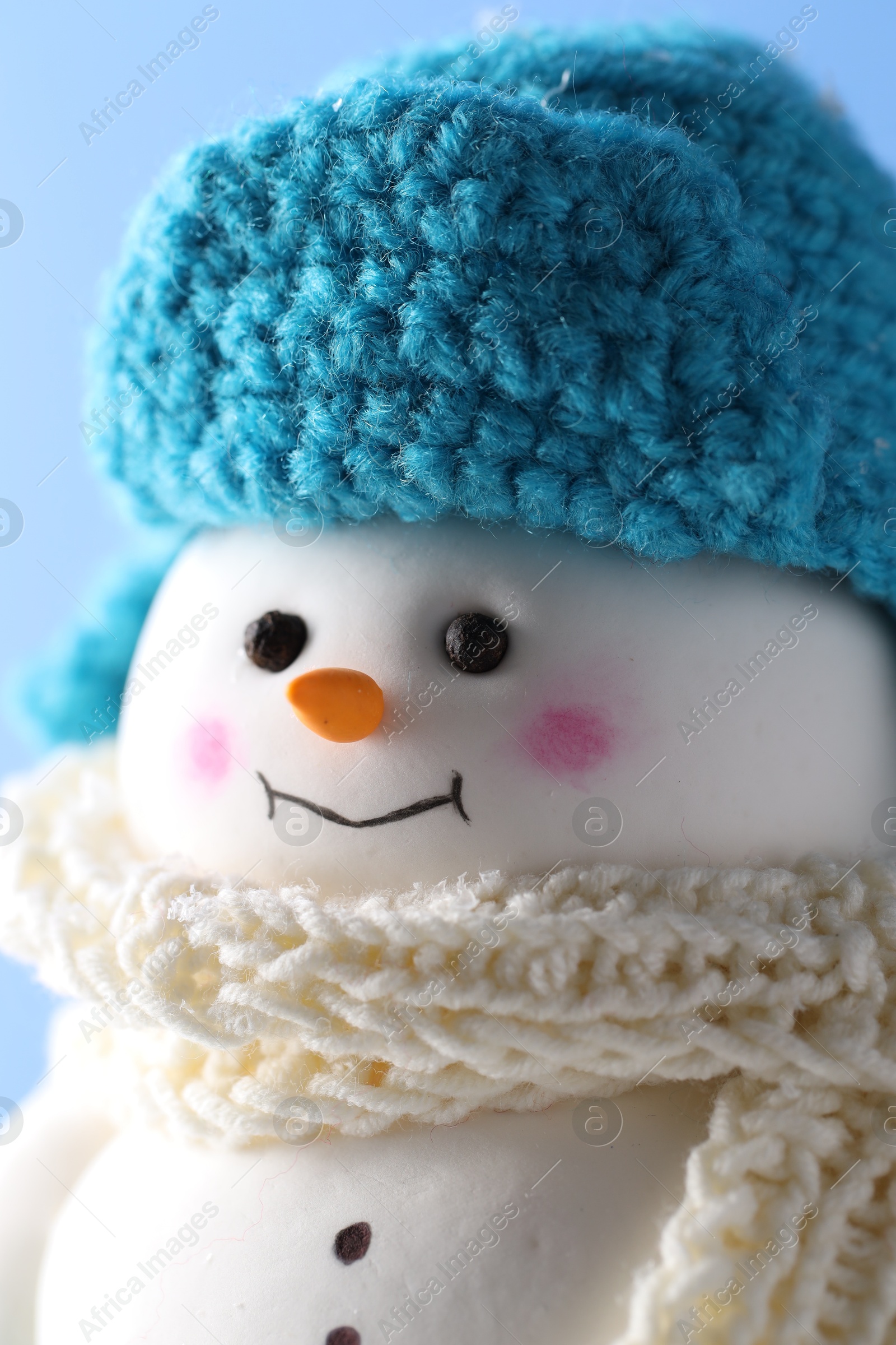 Photo of Cute decorative snowman against light blue background, closeup