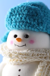 Photo of Cute decorative snowman against light blue background, closeup