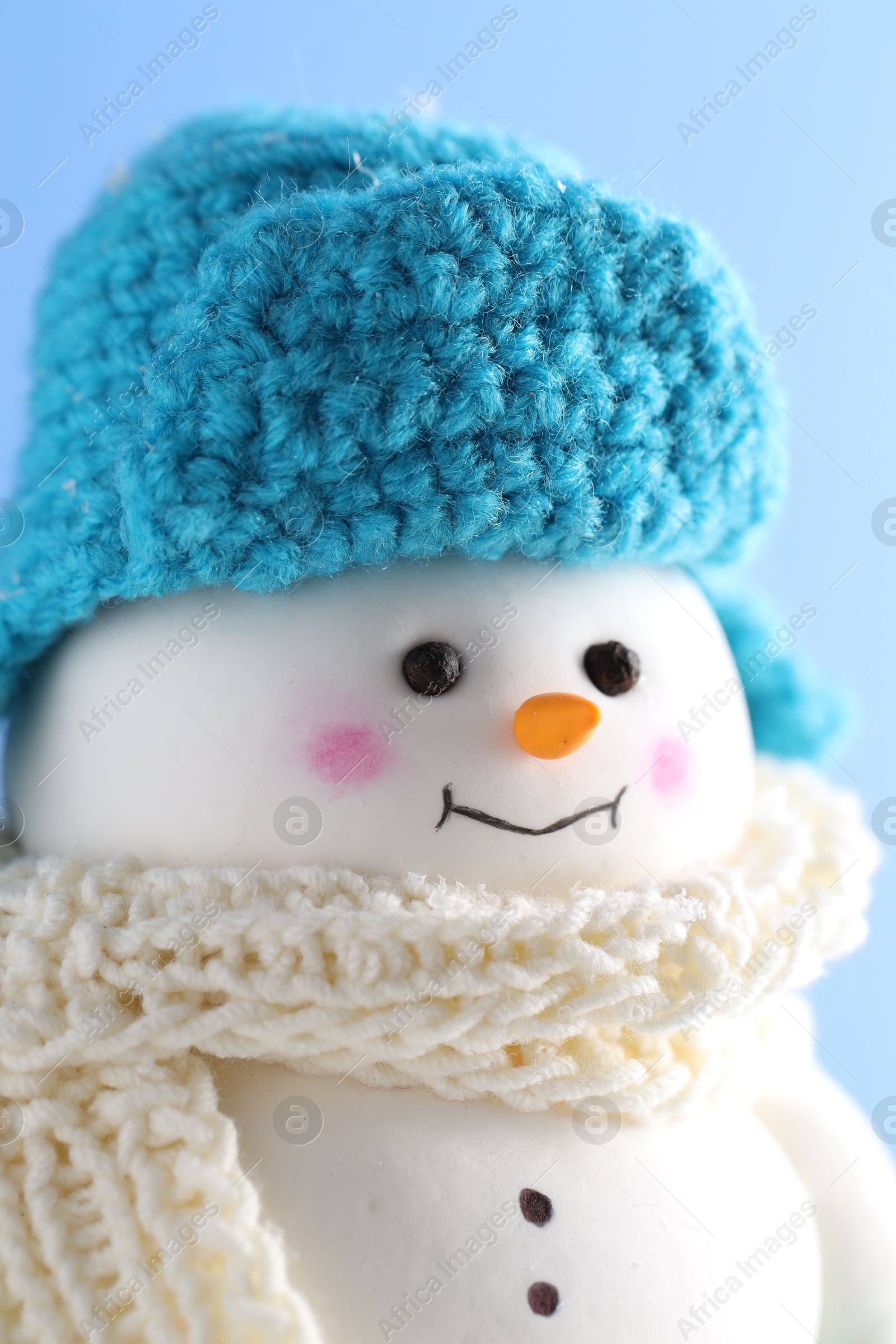 Photo of Cute decorative snowman against light blue background, closeup