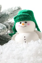 Photo of Cute decorative snowman and fir tree branches on artificial snow against white background, closeup