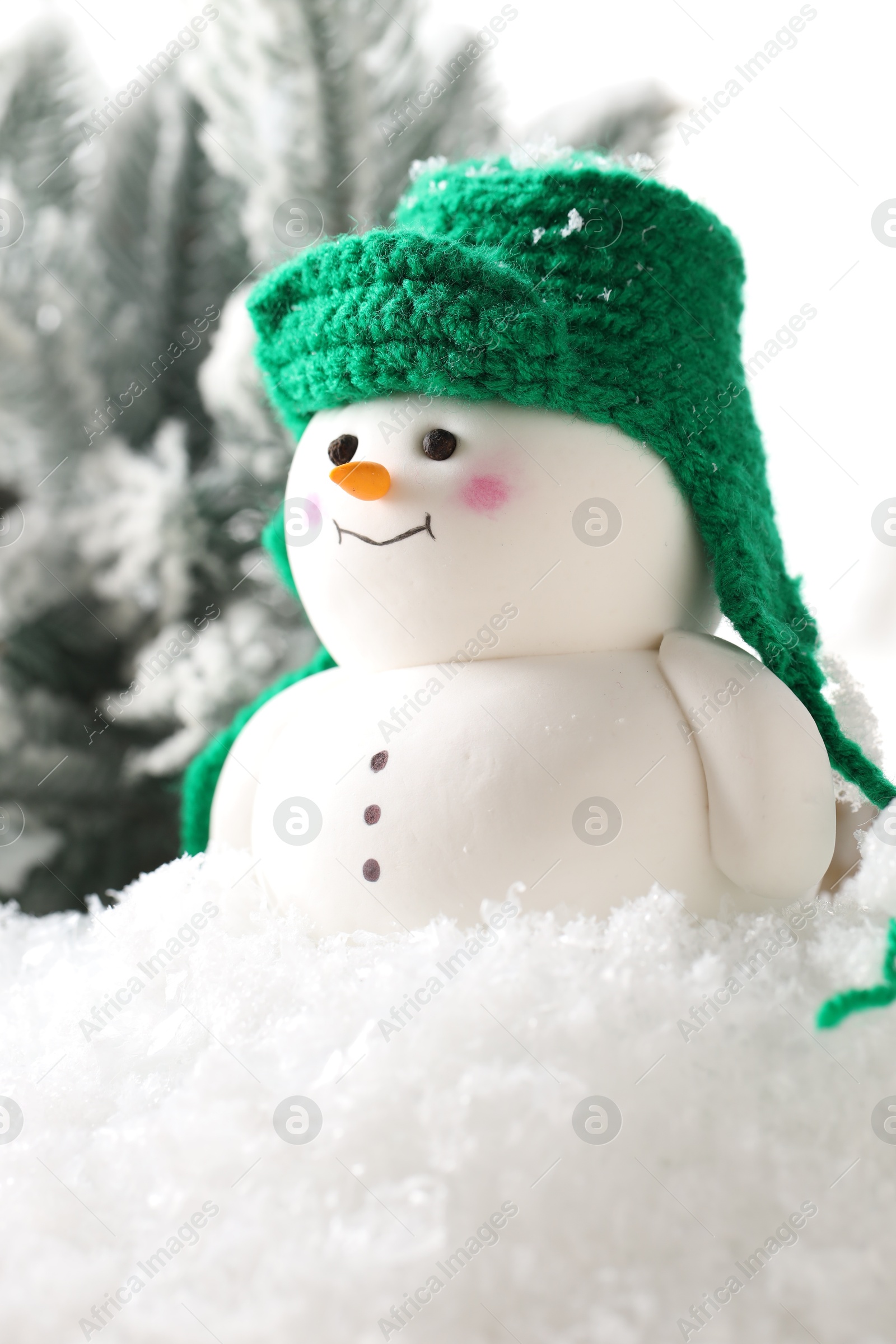 Photo of Cute decorative snowman and fir tree branches on artificial snow against white background, closeup