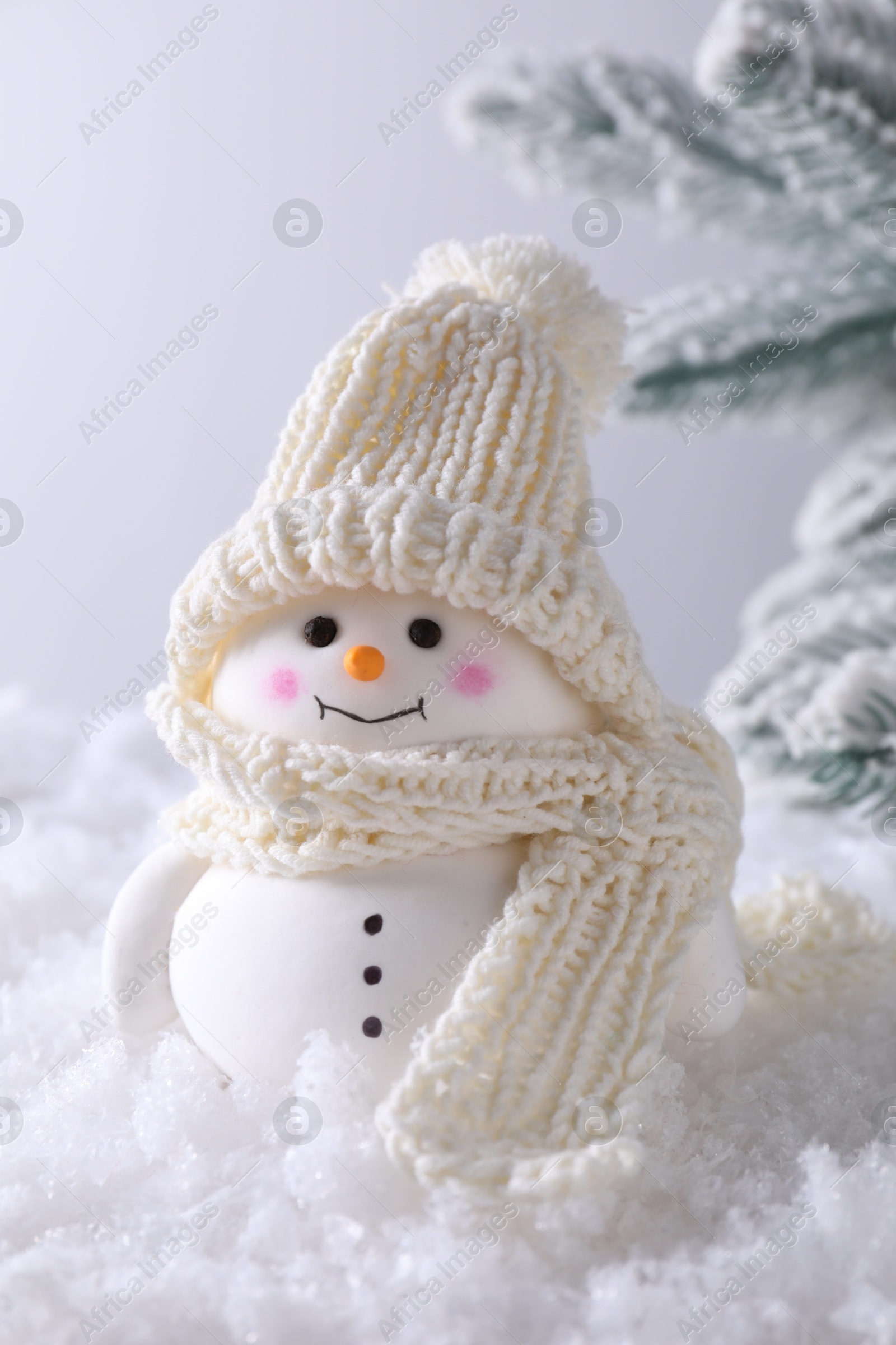 Photo of Cute decorative snowman on artificial snow against light background