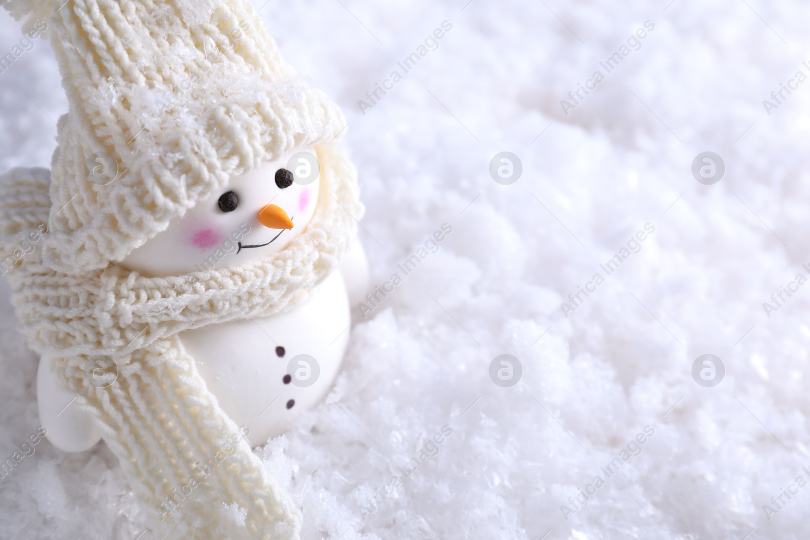 Photo of Cute decorative snowman on artificial snow, closeup. Space for text