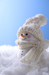 Photo of Cute decorative snowman on artificial snow against light blue background