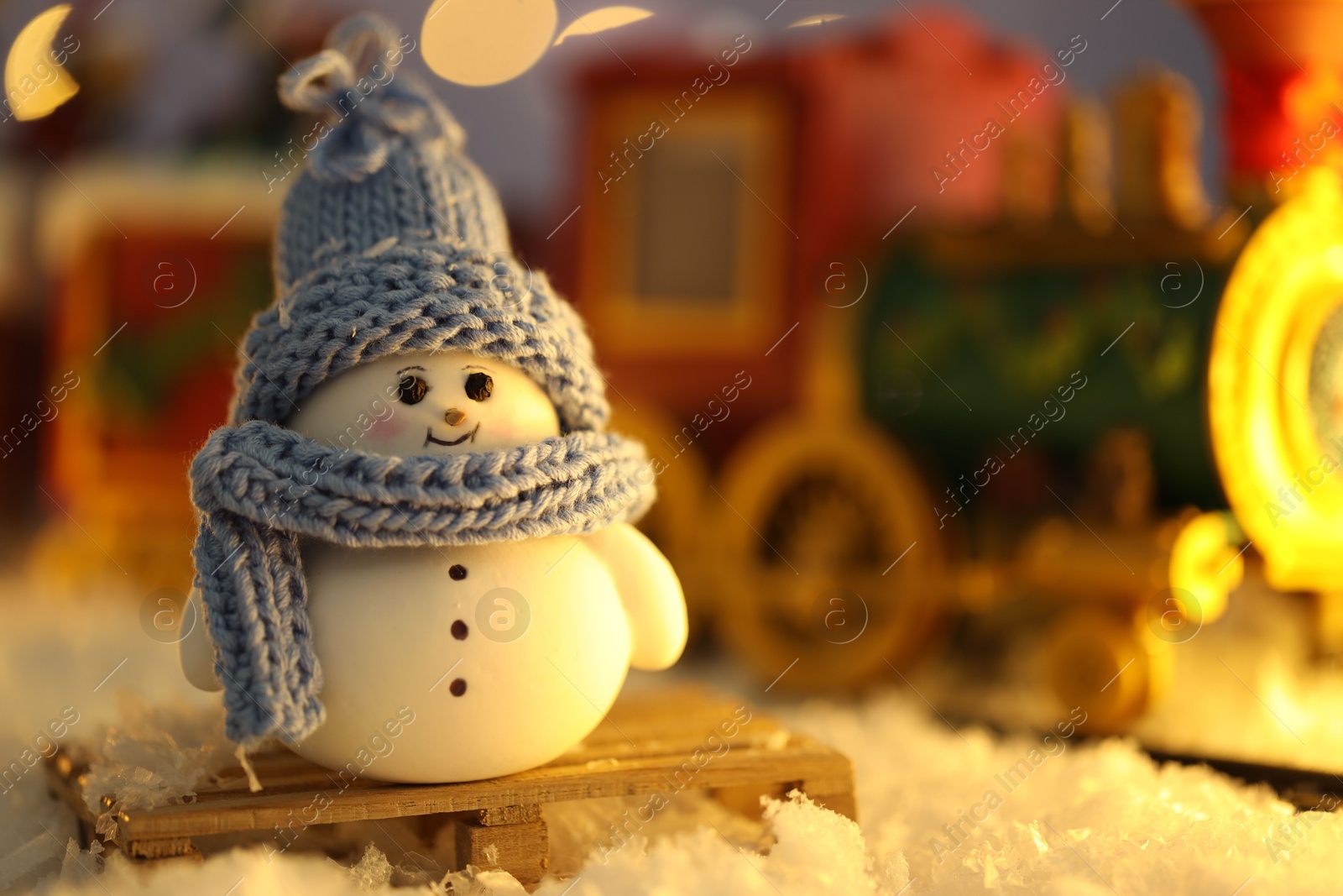 Photo of Cute decorative snowman on artificial snow against blurred background, closeup