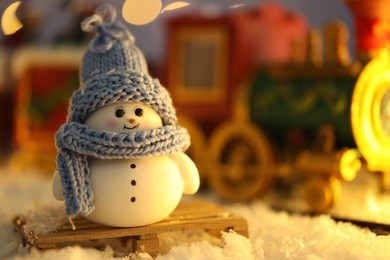 Photo of Cute decorative snowman on artificial snow against blurred background, closeup