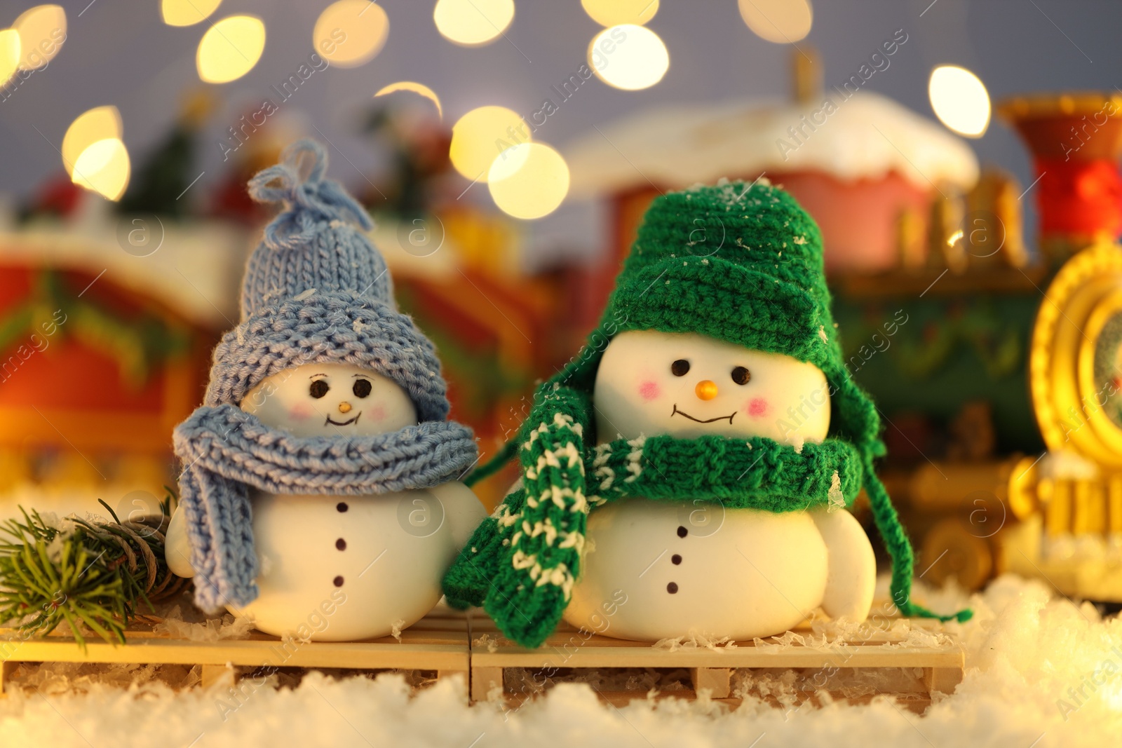 Photo of Cute decorative snowmen on artificial snow against blurred background, closeup