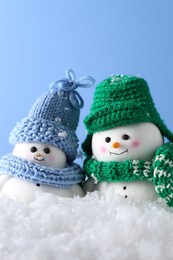 Photo of Cute decorative snowmen against light blue background, closeup