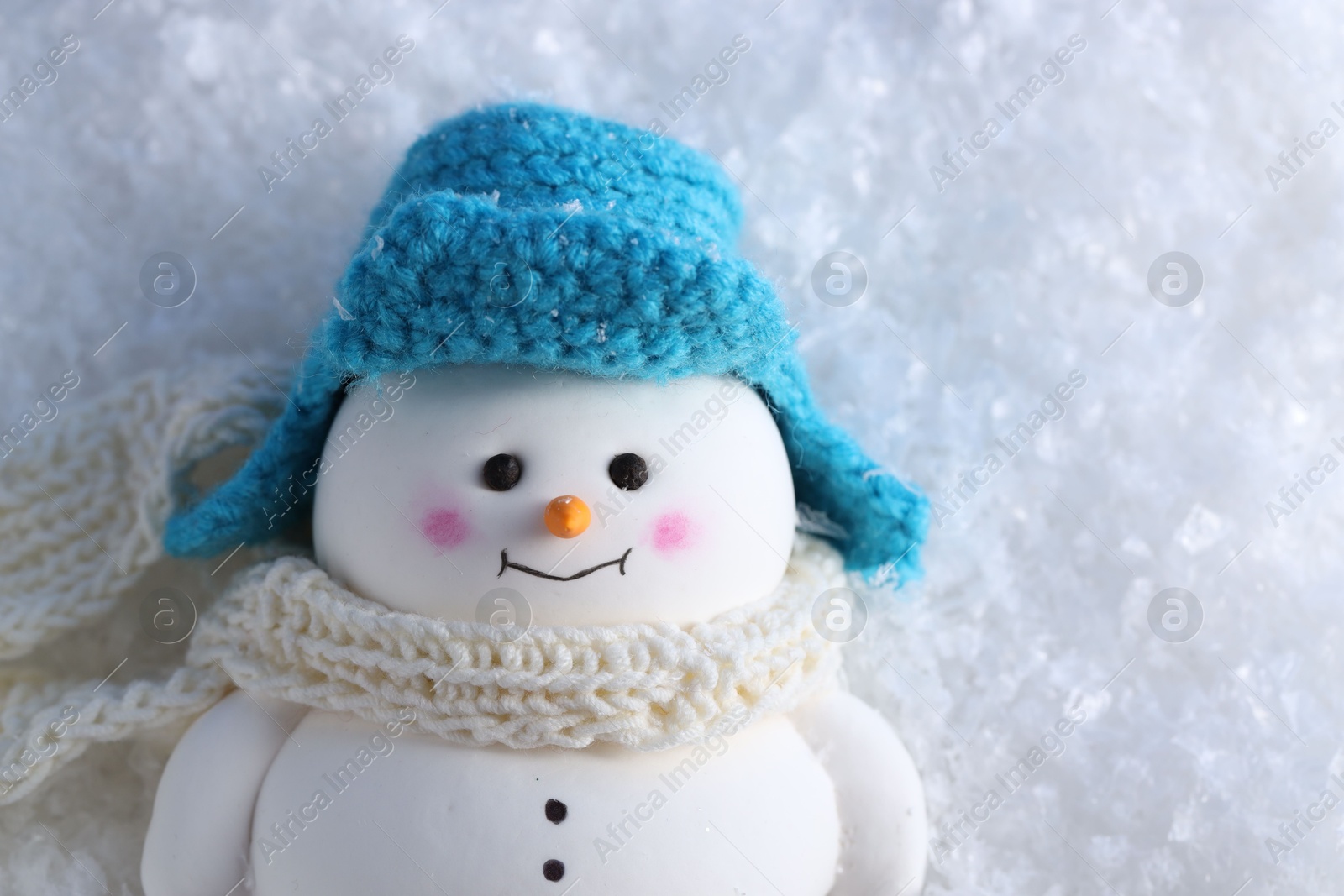 Photo of Cute decorative snowman on artificial snow, top view