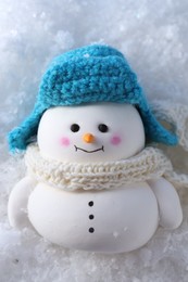 Photo of Cute decorative snowman on artificial snow, top view