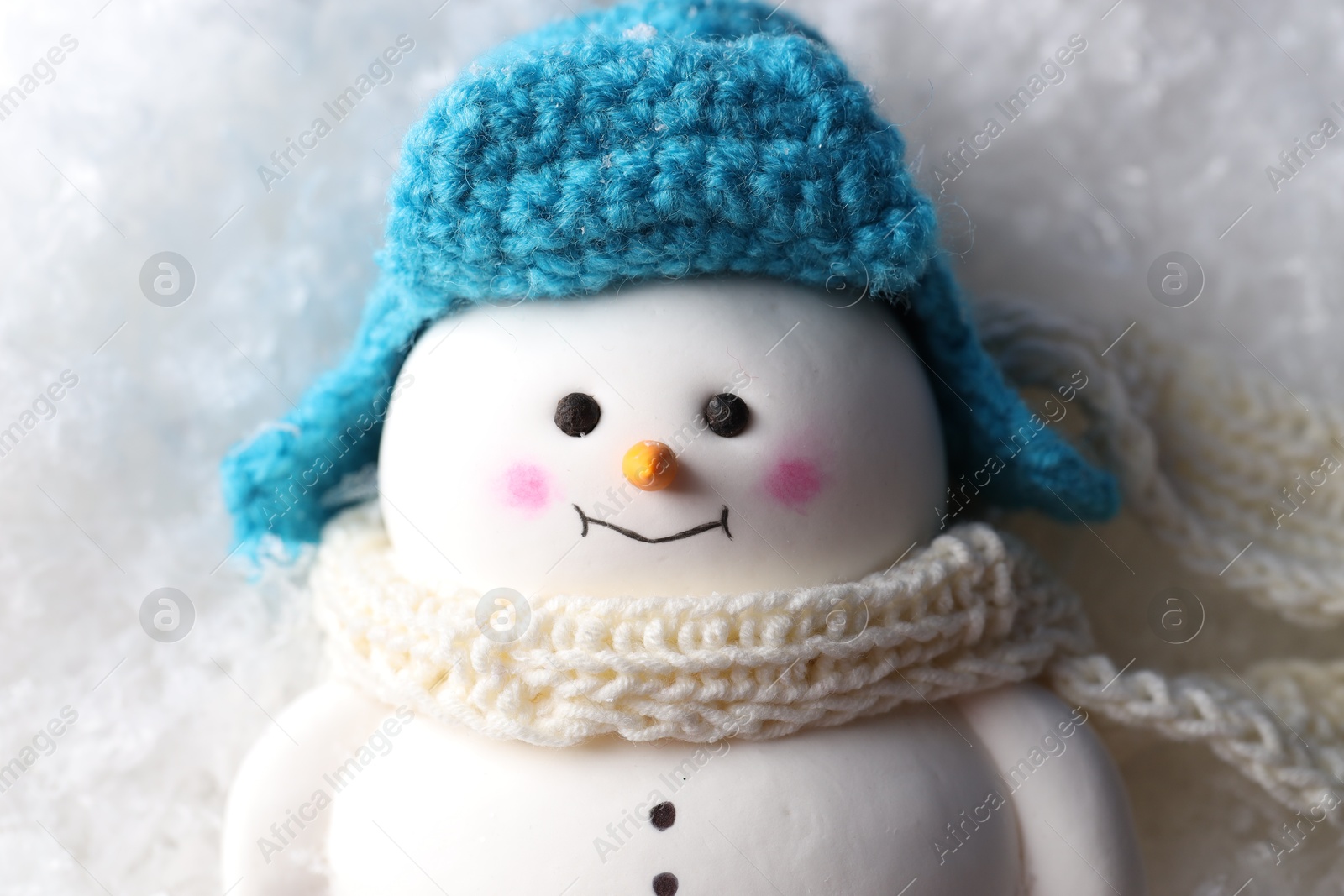 Photo of Cute decorative snowman on artificial snow, top view