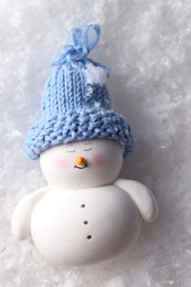 Photo of Cute decorative snowman on artificial snow, top view