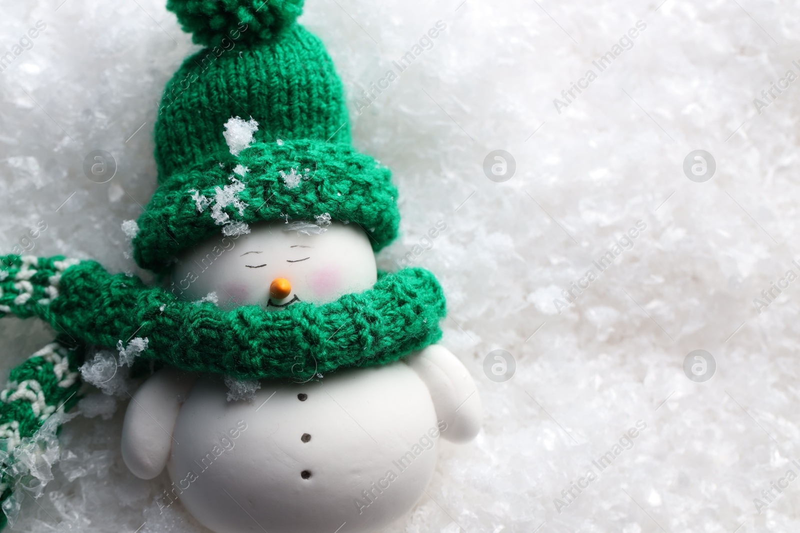 Photo of Cute decorative snowman on artificial snow, top view. Space for text