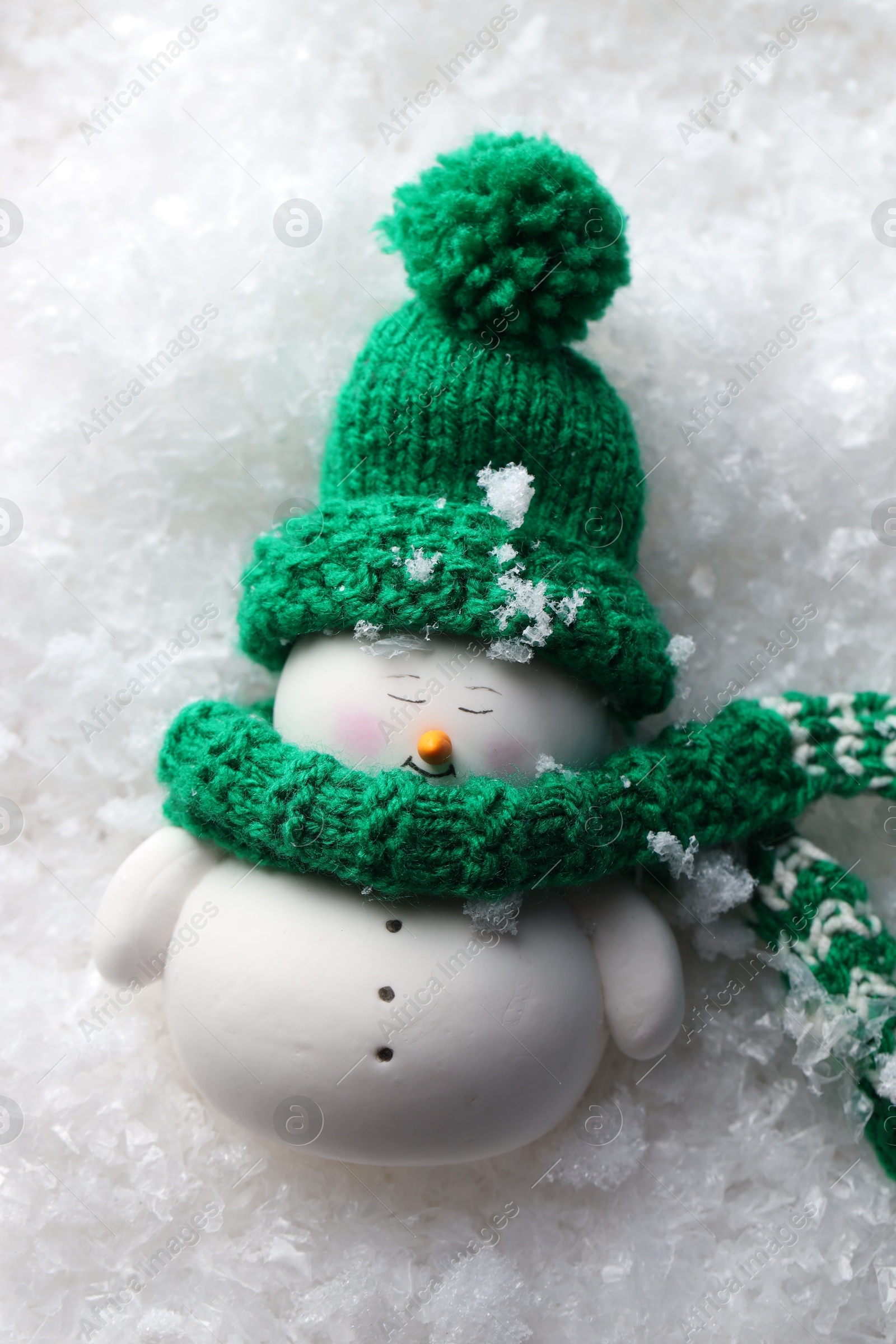 Photo of Cute decorative snowman on artificial snow, top view