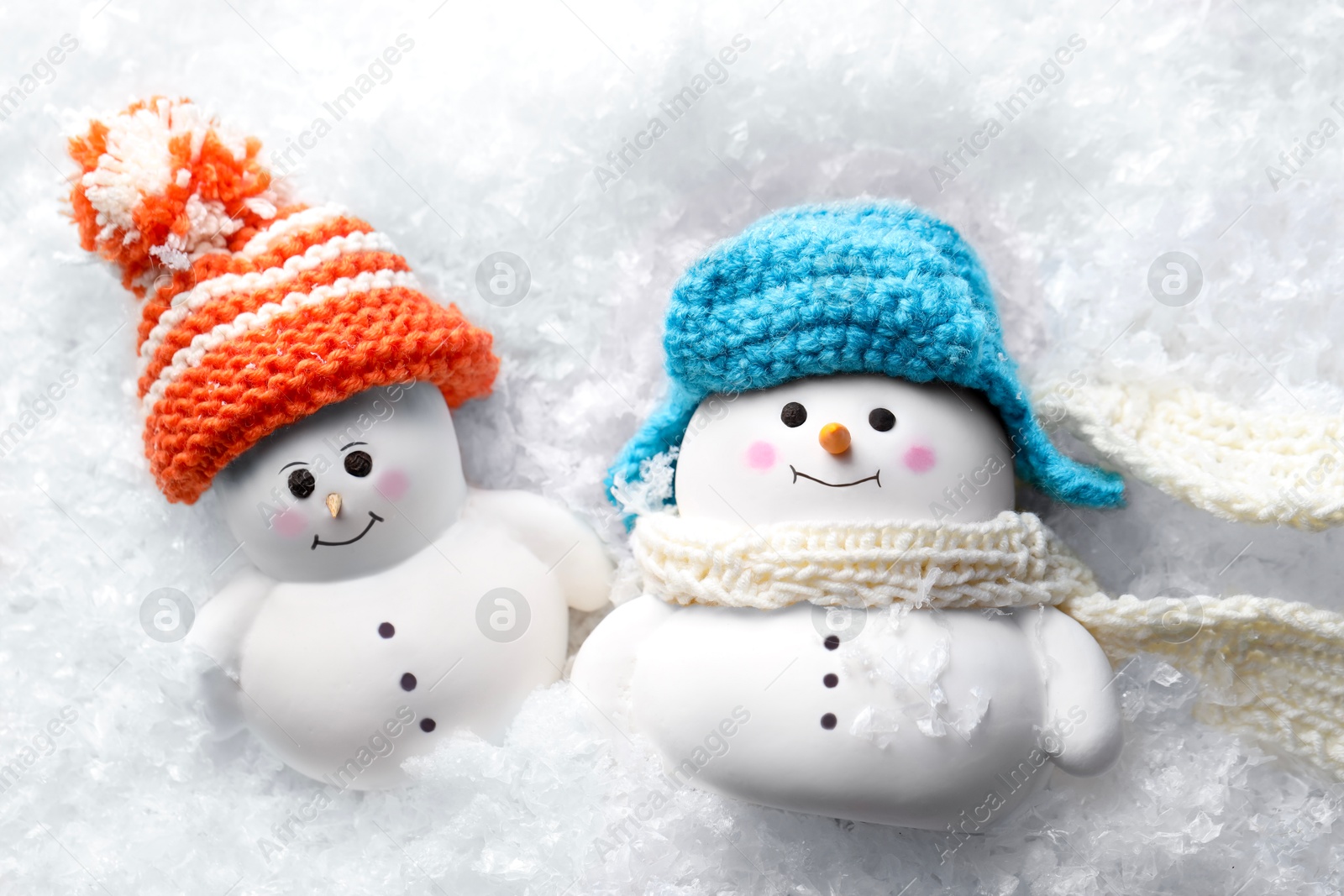 Photo of Cute decorative snowmen on artificial snow, top view