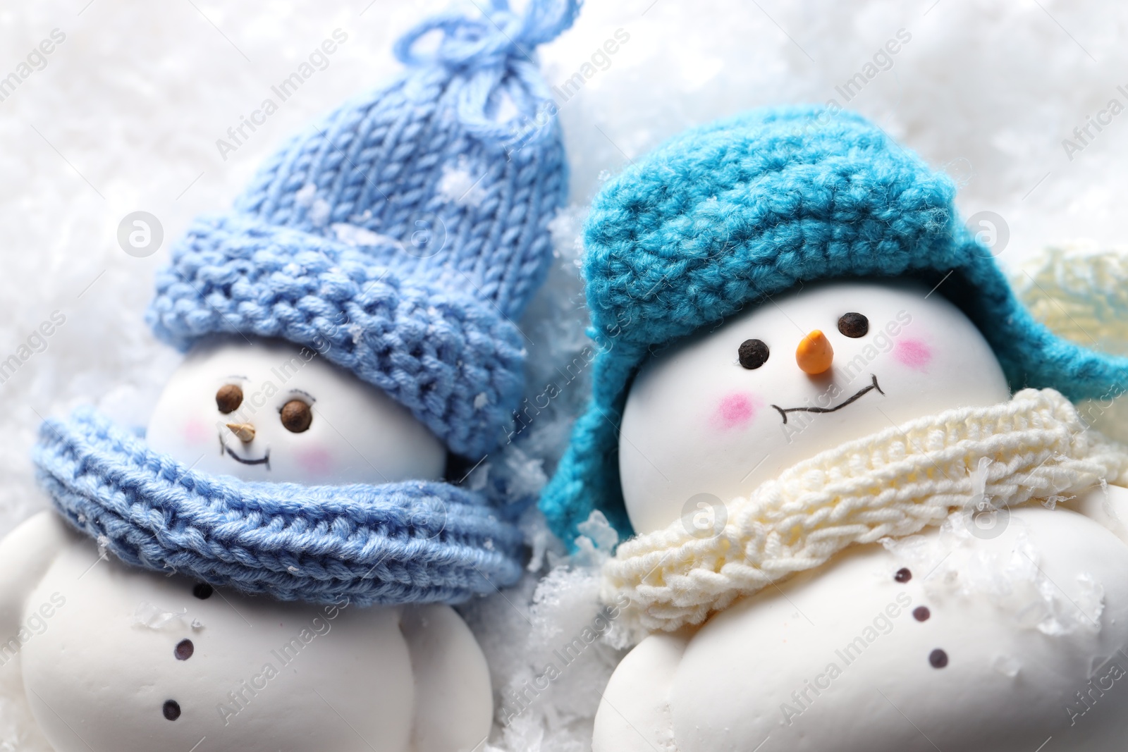 Photo of Cute decorative snowmen on artificial snow, closeup