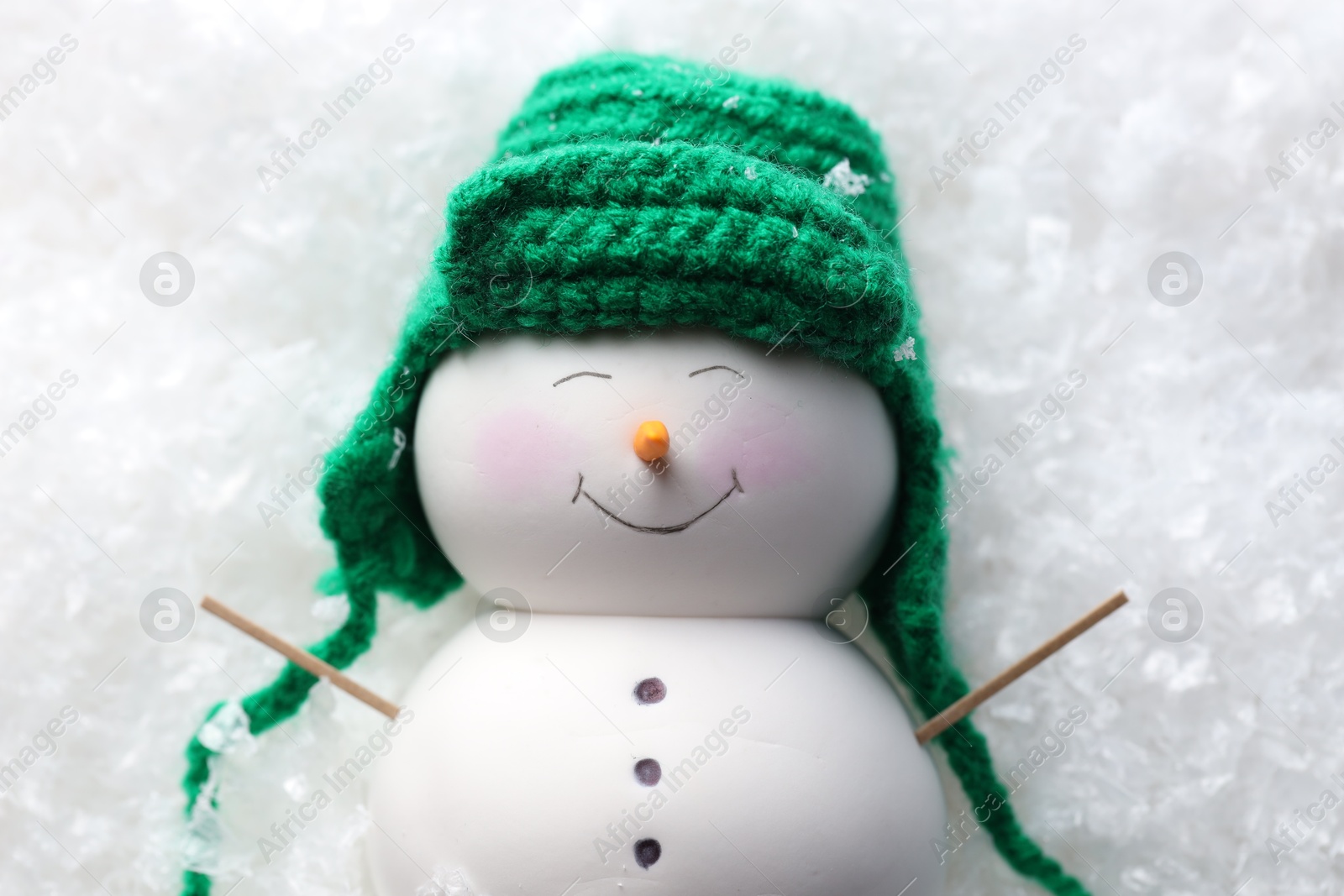 Photo of Cute decorative snowman on artificial snow, top view