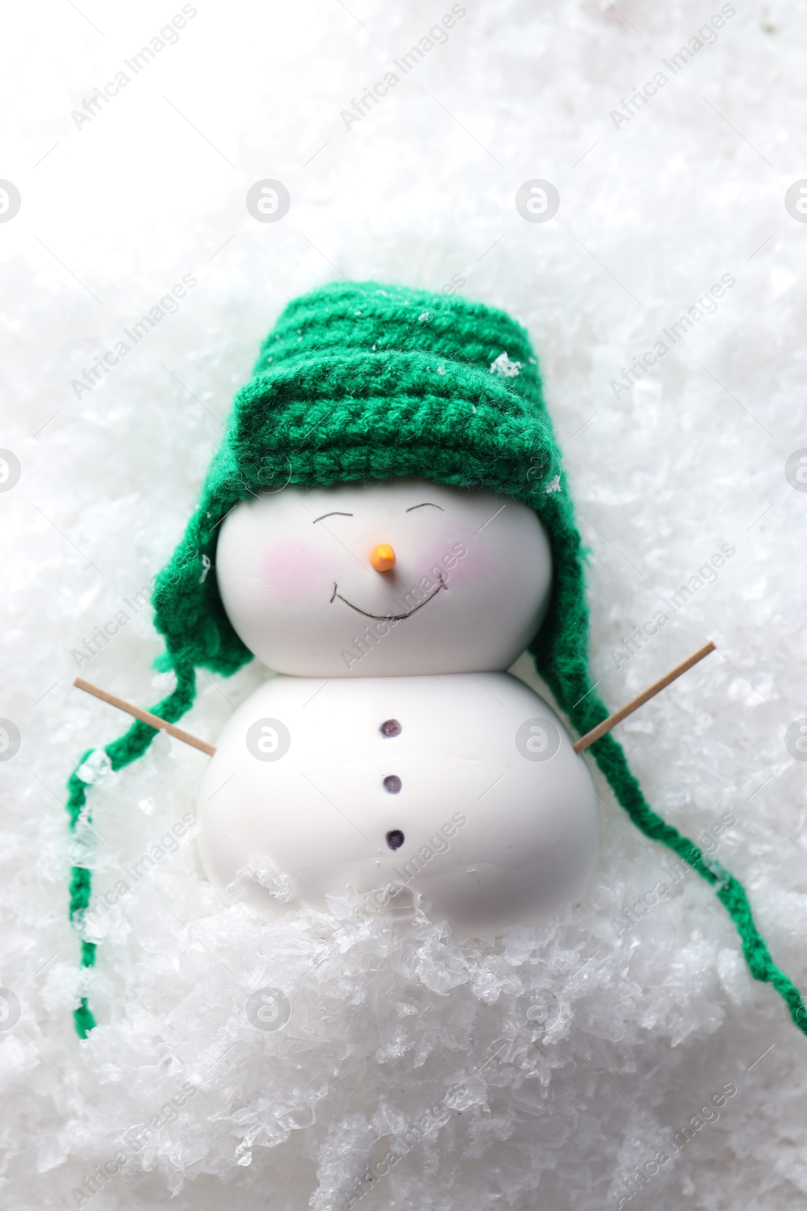 Photo of Cute decorative snowman on artificial snow, top view