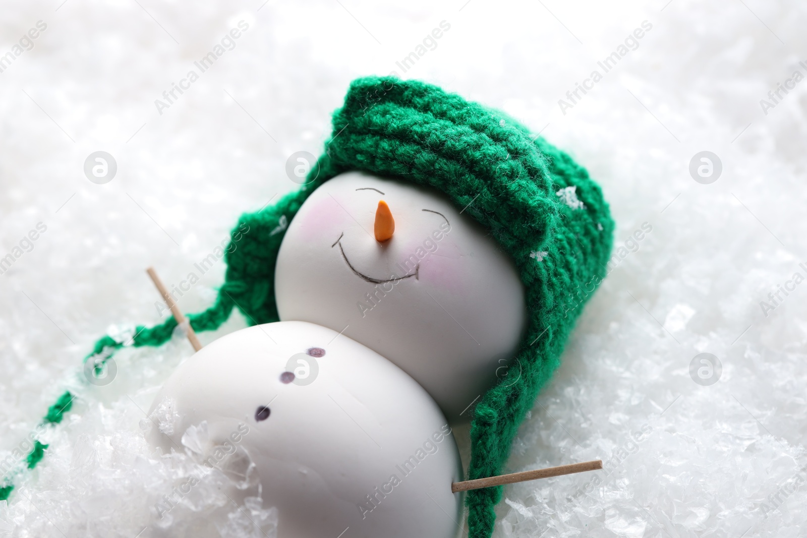 Photo of Cute decorative snowman on artificial snow, closeup