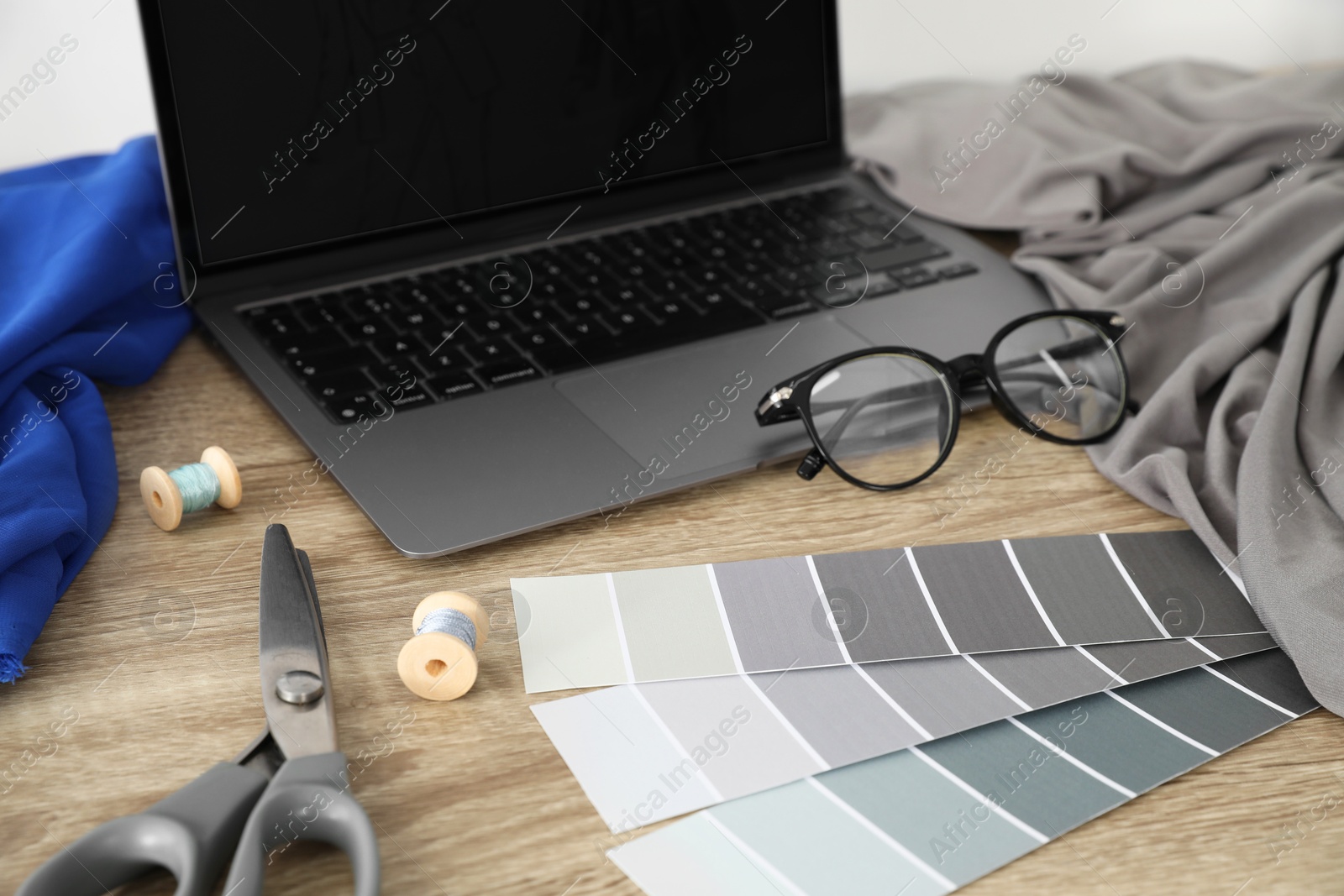 Photo of Laptop and different designer`s supplies on wooden table in workshop