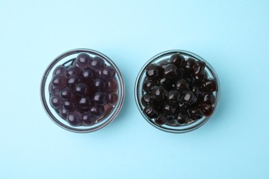 Photo of Dark tapioca pearls in bowls on light blue background, top view