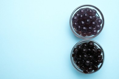 Photo of Tapioca pearls in bowls on light blue background, top view. Space for text