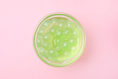 Photo of Bright tapioca pearls in bowl on pink background, top view