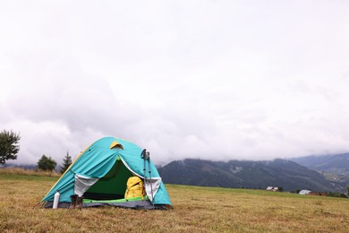 Photo of Camping tent and tourist stuff on grass in mountains, space for text