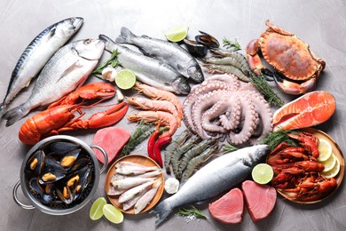 Many different sea food, herbs and lime on grey textured table, flat lay