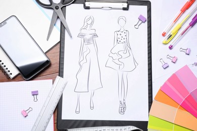 Photo of Sketch of stylish clothes and other fashion designer`s supplies on wooden table, flat lay