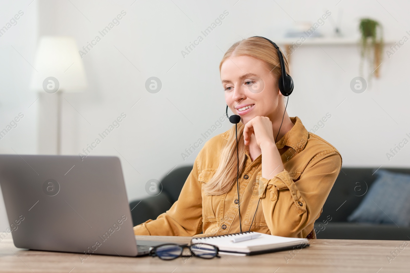 Photo of Interpreter in headset working with laptop at table indoors