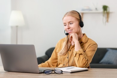 Interpreter in headset working with laptop at table indoors