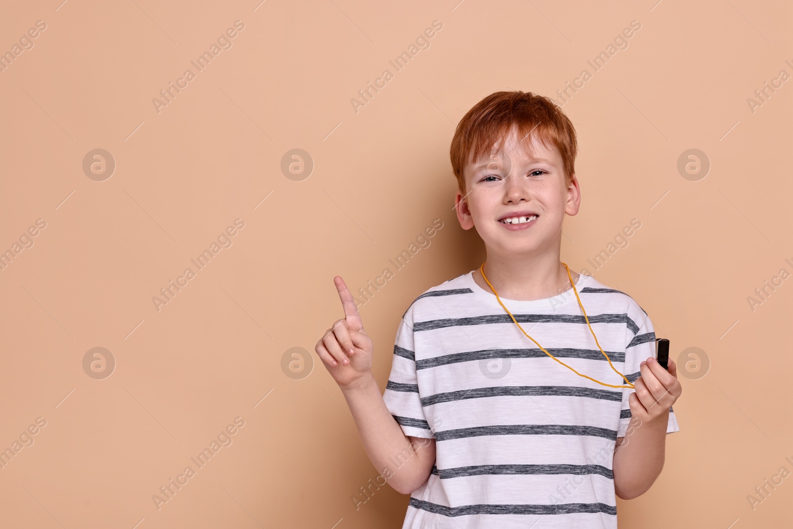 Photo of Little boy with whistle on beige background, space for text