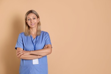 Photo of Portrait of nurse in medical uniform with badge on beige background, space for text