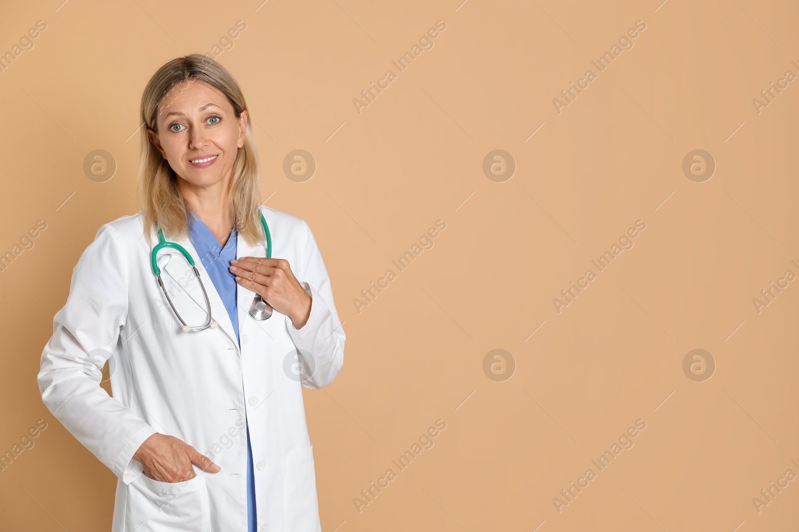 Photo of Portrait of doctor in medical uniform with stethoscope on beige background, space for text