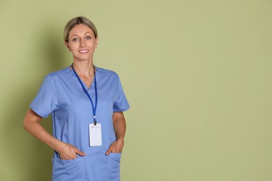 Portrait of nurse in medical uniform with badge on light green background, space for text