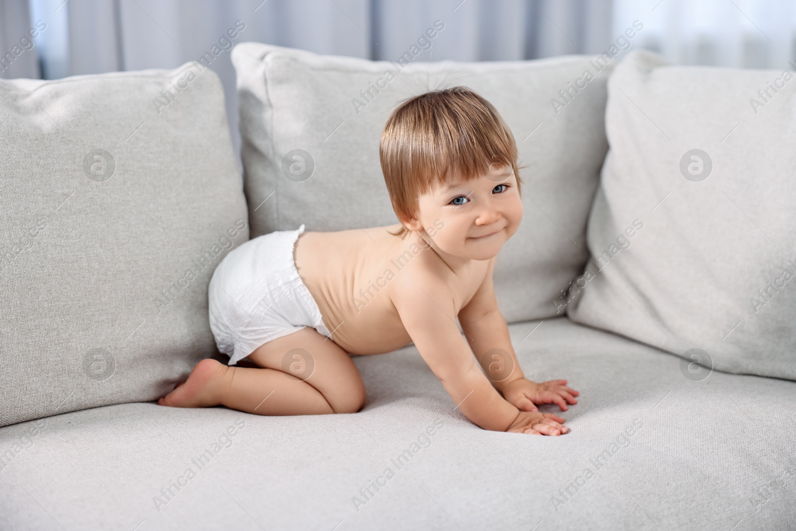 Photo of Little child in diaper on sofa at home