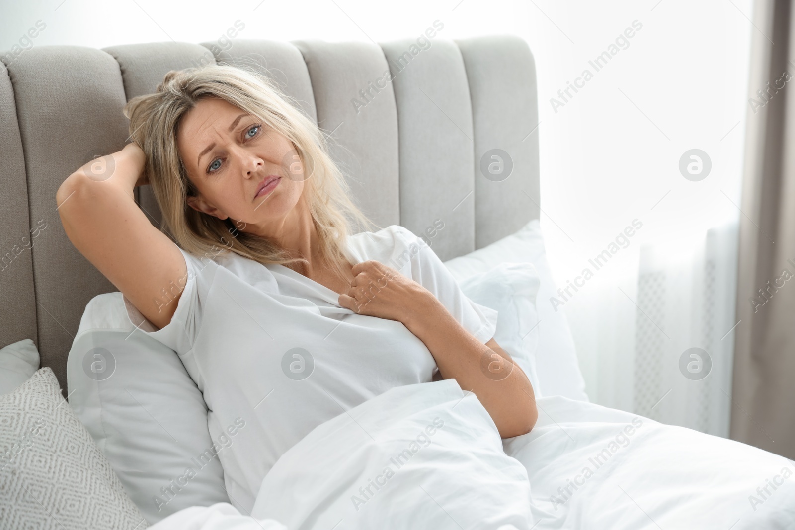 Photo of Menopause. Woman suffering from hot flash in bed at home, space for text