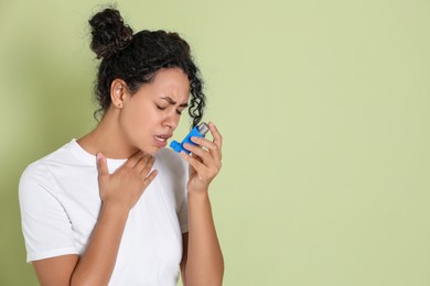 Photo of Young woman using asthma inhaler on light green background. Space for text