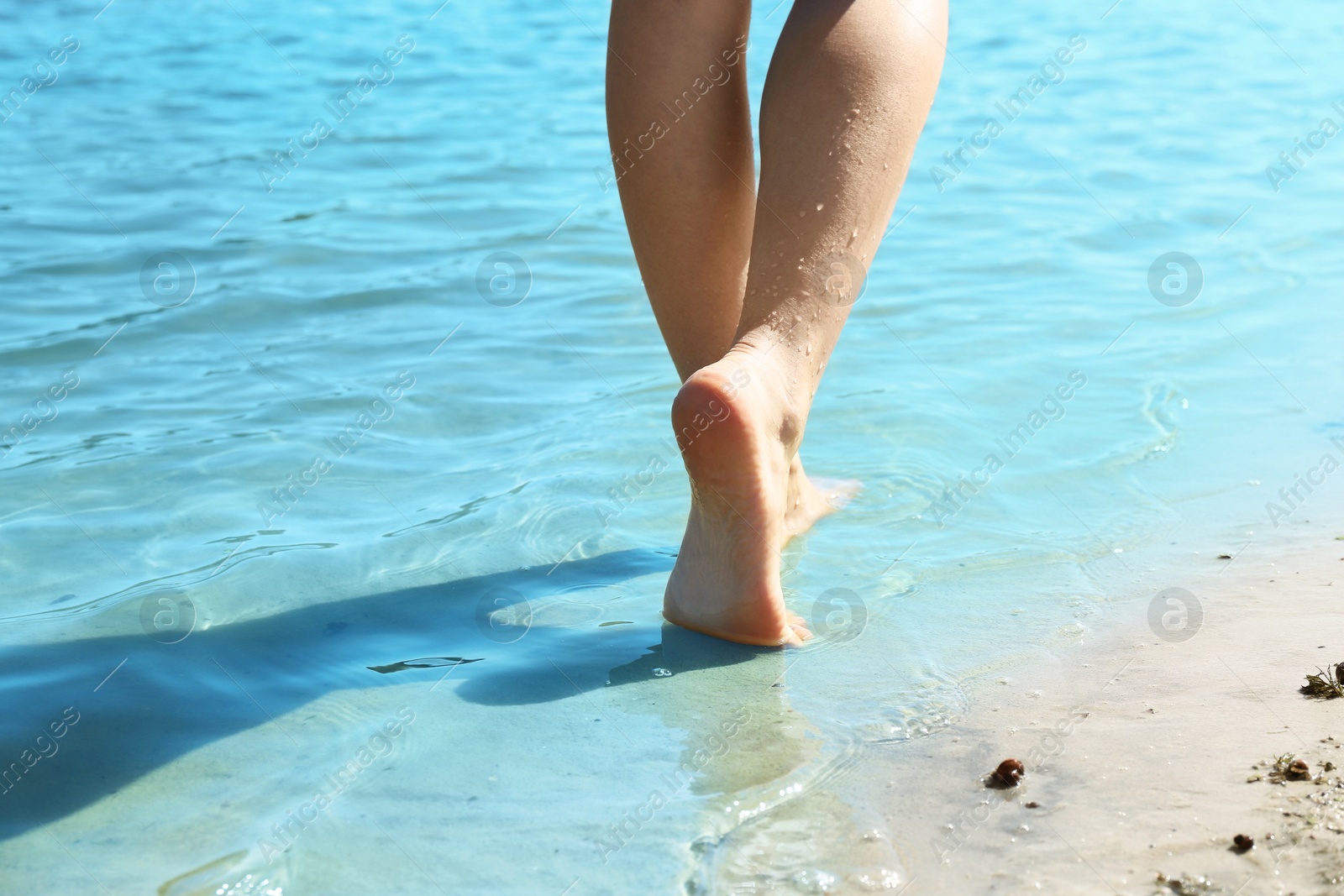 Photo of Woman walking barefoot through water on riverbank, closeup