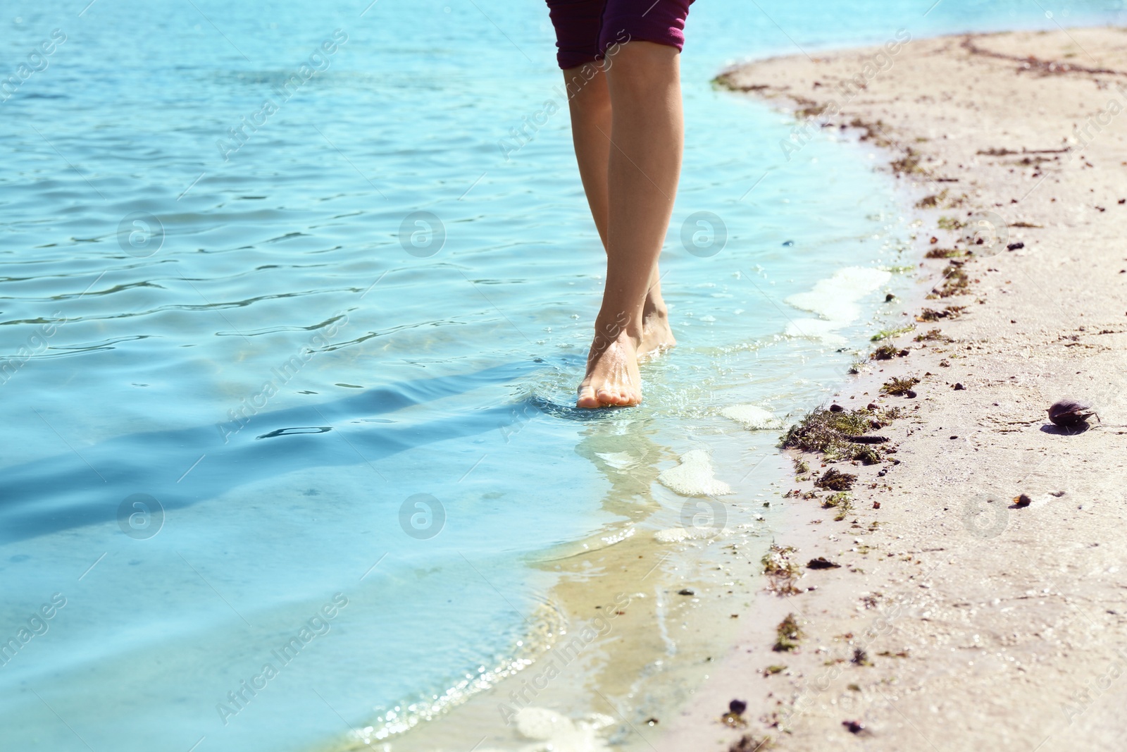 Photo of Woman walking barefoot through water on riverbank, closeup