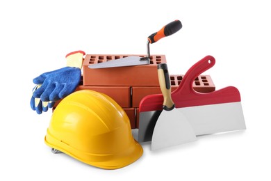 Photo of Yellow hard hat, red bricks, gloves, trowel and putty knives isolated on white. Building material and construction tools