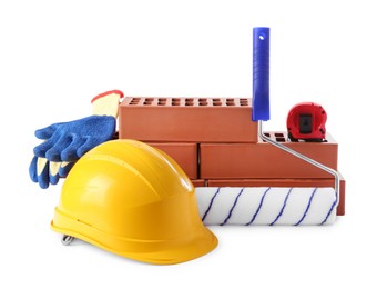 Photo of Yellow hard hat, red bricks, gloves, roller and measuring tape isolated on white. Building material and construction tools