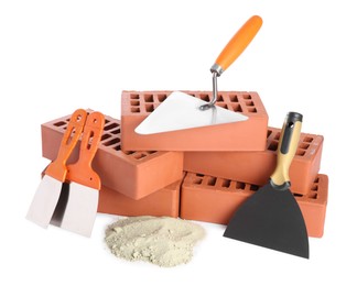 Photo of Trowel, putty knives, cement powder and red bricks isolated on white. Building materials and construction tools